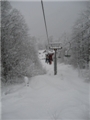 Заснеженные деревья окружают поднимающихся лыжников и сноубордистов